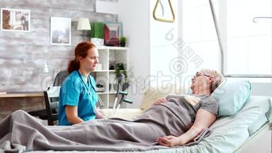 养老院的护士和躺在病床上的一位老太太谈话